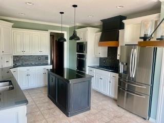 3805 Highridge, Edmond, OK 73003 - kitchen featuring appliances with stainless steel finishes, dark countertops, tasteful backsplash, a center island, and pendant lighting