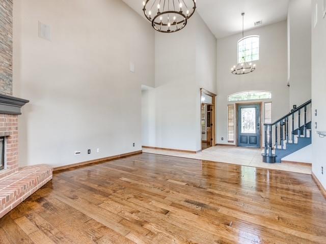 3805 Highridge, Edmond, OK 73003 - entrance foyer with a chandelier, hardwood / wood-style flooring, high vaulted ceiling, a fireplace, and stairway