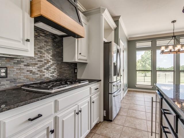 3805 Highridge, Edmond, OK 73003 - kitchen featuring stainless steel appliances, ornamental molding, range hood, decorative backsplash, and white cabinetry
