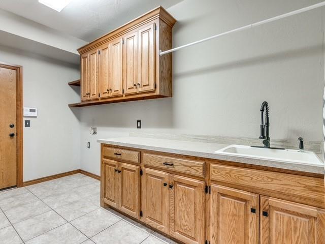 3805 Highridge, Edmond, OK 73003 - laundry area featuring cabinet space, light tile patterned floors, and hookup for a washing machine
