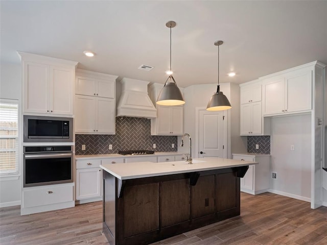 19608 Dalemead Way, Edmond, OK 73012 - kitchen with stainless steel oven, custom exhaust hood, built in microwave, black gas stovetop, and white cabinets