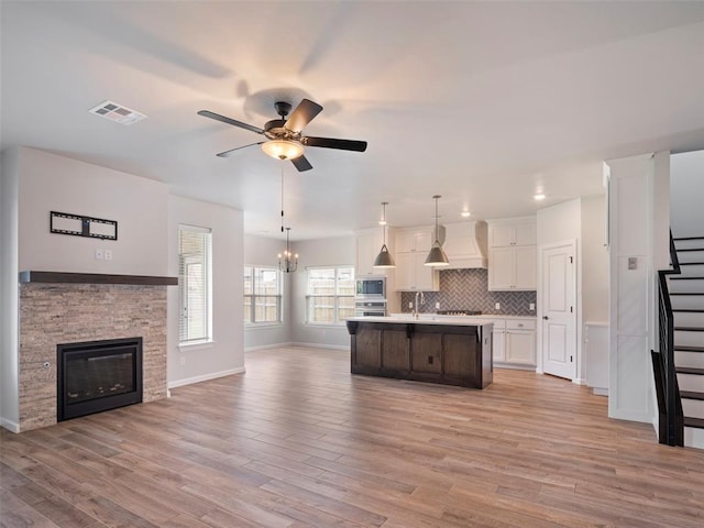 19608 Dalemead Way, Edmond, OK 73012 - kitchen featuring open floor plan, wall chimney exhaust hood, light countertops, ceiling fan, and white cabinetry