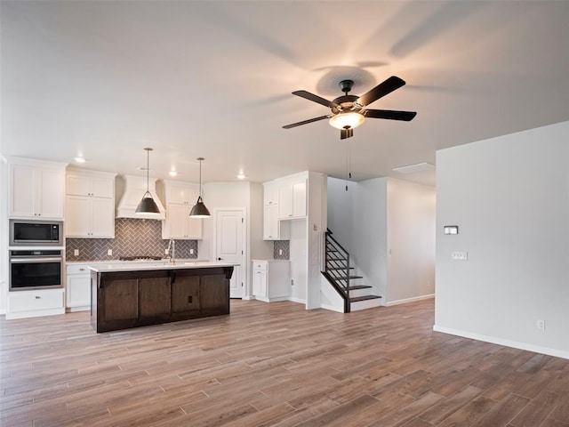 19608 Dalemead Way, Edmond, OK 73012 - kitchen featuring built in microwave, stainless steel oven, custom range hood, white cabinetry, and a ceiling fan