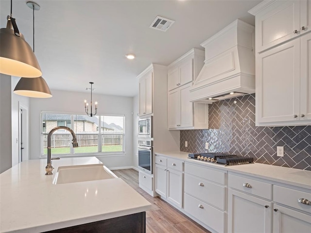 19608 Dalemead Way, Edmond, OK 73012 - kitchen featuring stainless steel appliances, light countertops, backsplash, light wood-style flooring, and white cabinets