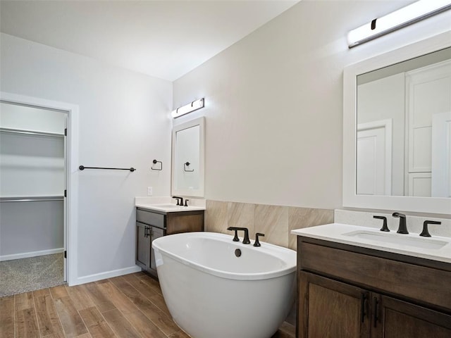19608 Dalemead Way, Edmond, OK 73012 - bathroom featuring a freestanding tub, a spacious closet, two vanities, and wood finished floors