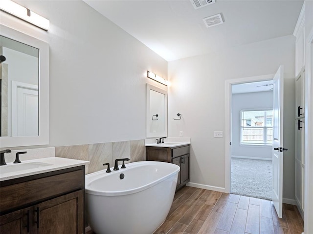 19608 Dalemead Way, Edmond, OK 73012 - full bath featuring a freestanding tub, two vanities, and wood finished floors