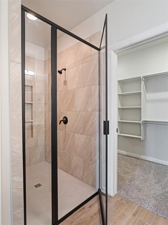 19608 Dalemead Way, Edmond, OK 73012 - full bathroom featuring a stall shower, wood finished floors, and a walk in closet