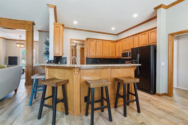 2917 Stafford Rd, Edmond, OK 73012 - kitchen featuring freestanding refrigerator, stainless steel microwave, ornamental molding, tasteful backsplash, and a peninsula