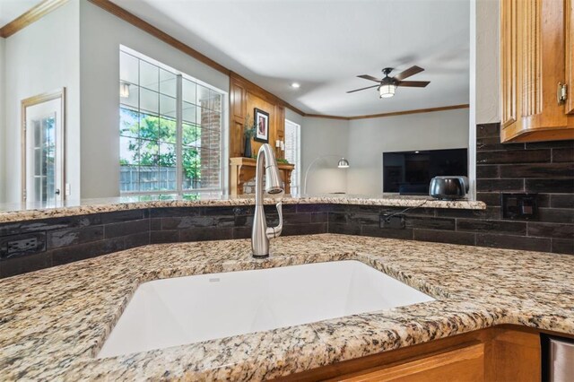 2917 Stafford Rd, Edmond, OK 73012 - kitchen with crown molding, light stone counters, a ceiling fan, backsplash, and open floor plan