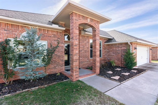 8300 NW 71st St, Oklahoma City, OK 73132 - doorway to property with brick siding, a garage, driveway, and a shingled roof