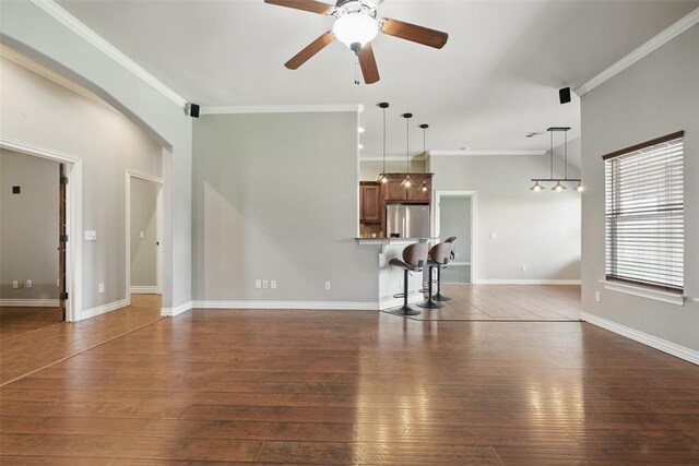 2716 Busheywood Dr, Yukon, OK 73099 - unfurnished living room featuring dark wood-style flooring, ceiling fan, crown molding, and arched walkways
