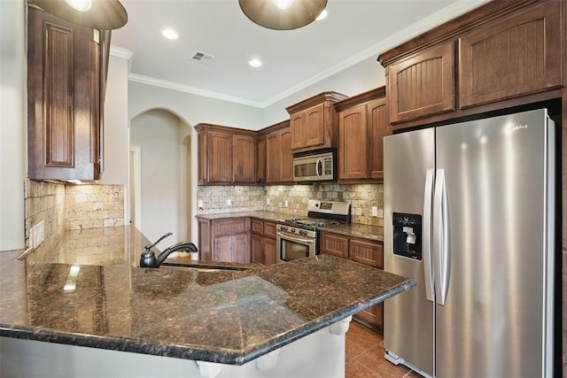2716 Busheywood Dr, Yukon, OK 73099 - kitchen with appliances with stainless steel finishes, a peninsula, crown molding, arched walkways, and dark stone countertops