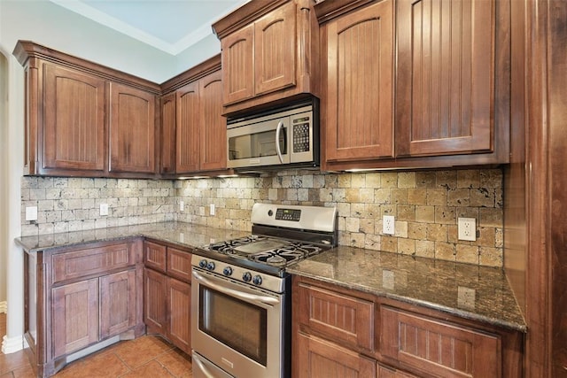 2716 Busheywood Dr, Yukon, OK 73099 - kitchen featuring appliances with stainless steel finishes, tasteful backsplash, dark stone counters, and light tile patterned floors