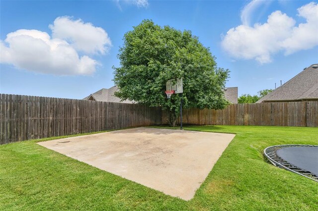 2716 Busheywood Dr, Yukon, OK 73099 - view of basketball court featuring basketball hoop, a fenced backyard, and a trampoline
