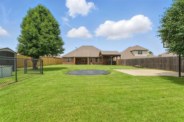 2716 Busheywood Dr, Yukon, OK 73099 - back of house featuring a patio, a trampoline, a fenced backyard, and brick siding