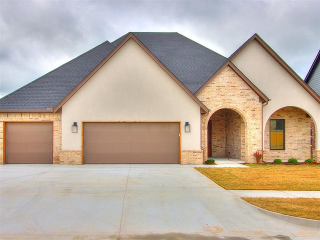 9320 NW 84th St, Yukon, OK 73099 - view of front of property with an attached garage, driveway, brick siding, and stucco siding