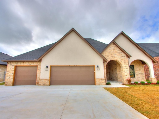 9320 NW 84th St, Yukon, OK 73099 - view of front facade featuring an attached garage, concrete driveway, brick siding, and stucco siding