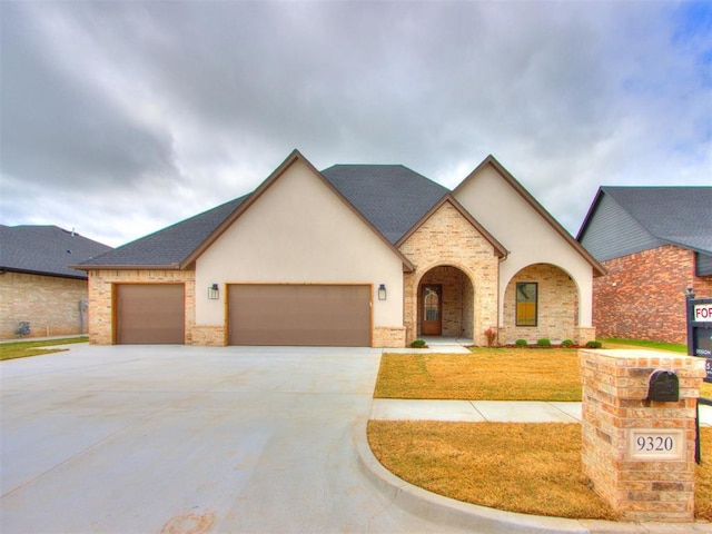 9320 NW 84th St, Yukon, OK 73099 - view of front facade with a garage, concrete driveway, stone siding, and a front lawn
