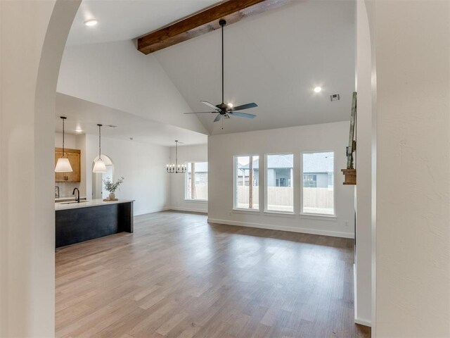 9320 NW 84th St, Yukon, OK 73099 - unfurnished living room with a ceiling fan, beamed ceiling, arched walkways, wood finished floors, and high vaulted ceiling