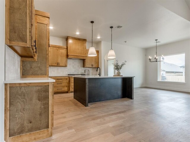 9320 NW 84th St, Yukon, OK 73099 - kitchen featuring tasteful backsplash, light wood-type flooring, premium range hood, light countertops, and a chandelier