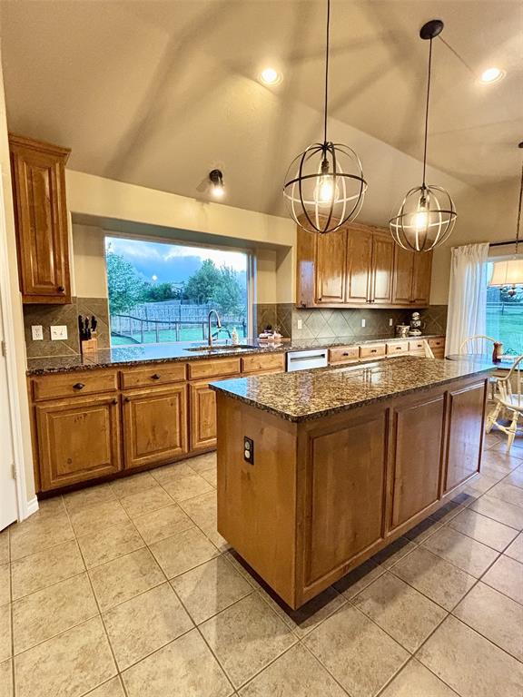 20301 Flowered Meadows Way, Edmond, OK 73012 - kitchen featuring brown cabinetry, a center island, tasteful backsplash, dishwasher, and lofted ceiling