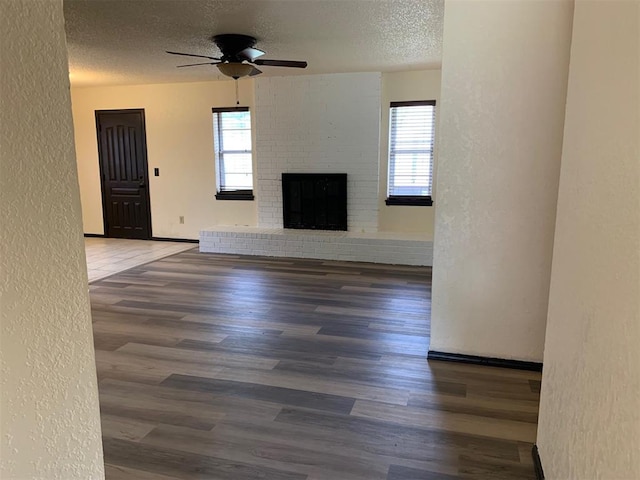 516 Ridgecrest Rd, Edmond, OK 73013 - unfurnished living room with a textured wall, a textured ceiling, ceiling fan, wood finished floors, and a fireplace