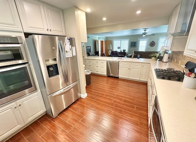 1516 N Hudson St, Altus, OK 73521 - kitchen featuring appliances with stainless steel finishes, wall chimney range hood, ceiling fan, light countertops, and open floor plan