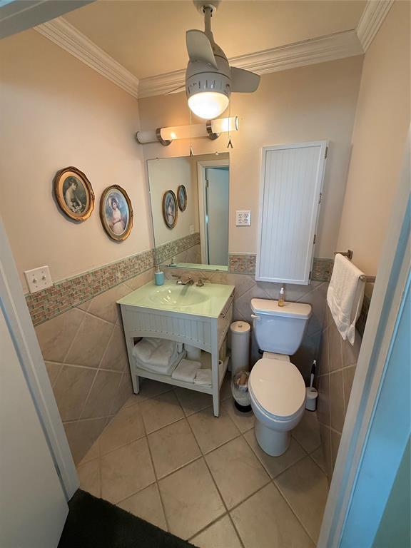 1516 N Hudson St, Altus, OK 73521 - bathroom with tile walls, tile patterned floors, ornamental molding, a wainscoted wall, and vanity
