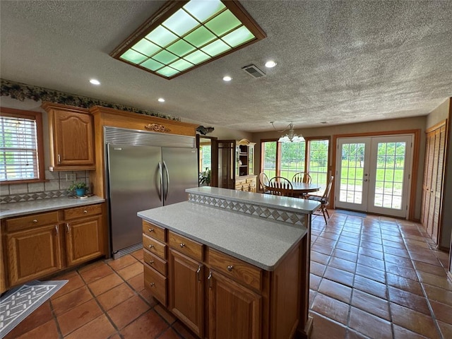 36166 Ew 1120th Rd, Seminole, OK 74868 - kitchen with stainless steel built in fridge, a textured ceiling, healthy amount of natural light, a center island, and brown cabinets