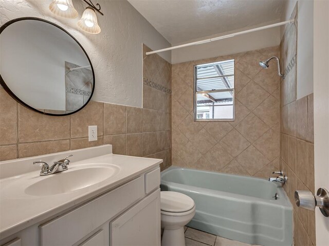 2805 SW 60th St, Oklahoma City, OK 73159 - full bath with tile walls, washtub / shower combination, vanity, tile patterned floors, and a textured wall