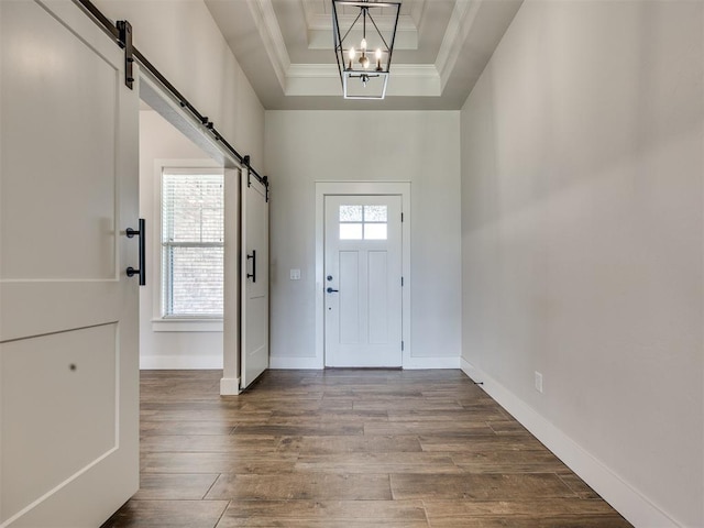16405 Brookefield Dr, Edmond, OK 73013 - foyer with a barn door, a raised ceiling, ornamental molding, healthy amount of natural light, and wood finished floors