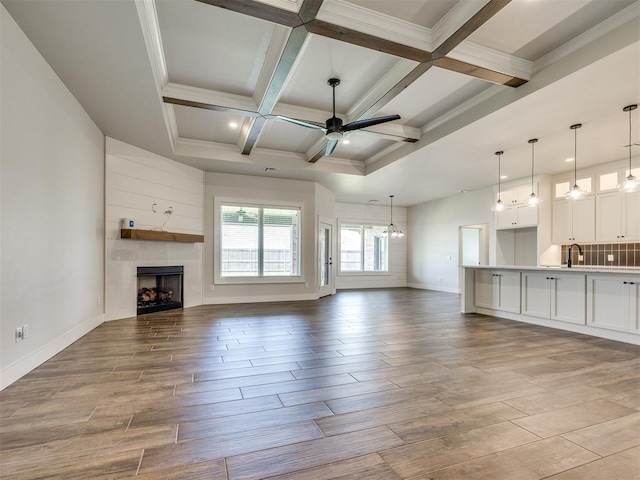16405 Brookefield Dr, Edmond, OK 73013 - unfurnished living room with a ceiling fan, a fireplace, wood finished floors, beamed ceiling, and coffered ceiling