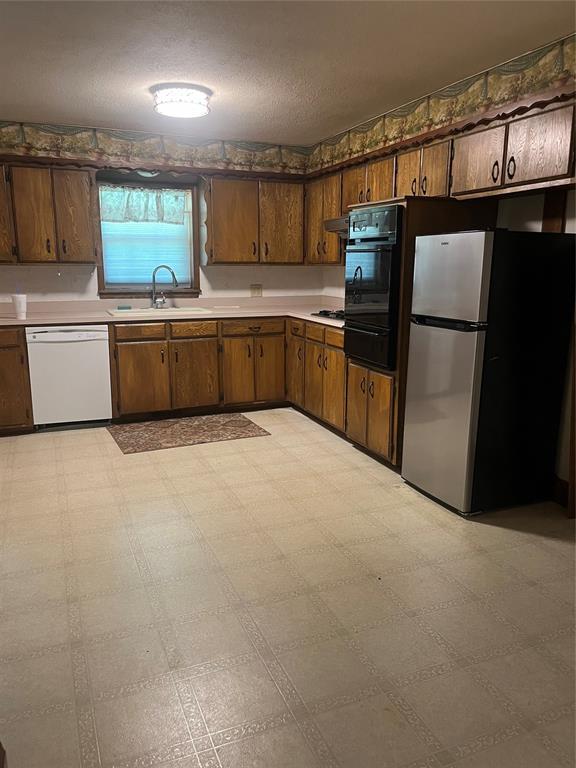 4179 W Gatlin St, Duncan, OK 73535 - kitchen featuring white dishwasher, freestanding refrigerator, black oven, light countertops, and light floors
