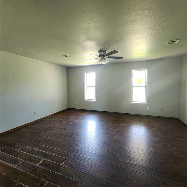 2413 7th St, Prague, OK 74864 - empty room with plenty of natural light, a ceiling fan, dark wood-type flooring, and a textured ceiling