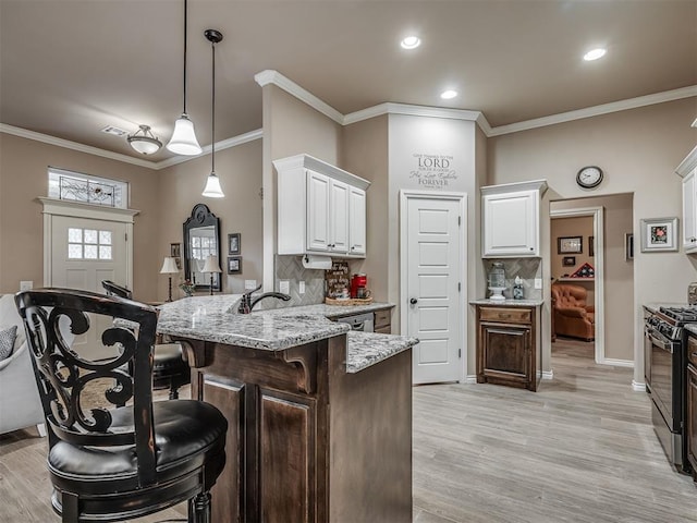2204 Cale Cv, Yukon, OK 73099 - kitchen with black range with gas cooktop, a peninsula, a kitchen bar, white cabinetry, and tasteful backsplash