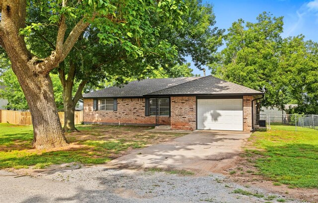311 N Monroe Ave, Blanchard, OK 73010 - view of front facade with a garage, asphalt driveway, roof with shingles, and brick siding
