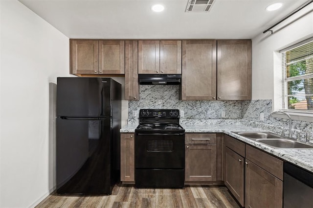 311 N Monroe Ave, Blanchard, OK 73010 - kitchen with black appliances, under cabinet range hood, wood finished floors, tasteful backsplash, and recessed lighting