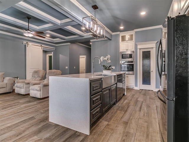 12917 Treemont Ln, Oklahoma City, OK 73142 - kitchen featuring stainless steel appliances, wood finished floors, a barn door, white cabinets, and light countertops