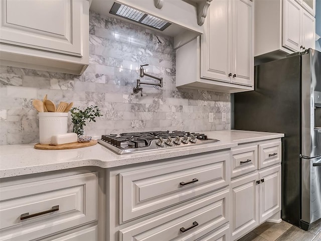 12917 Treemont Ln, Oklahoma City, OK 73142 - kitchen with appliances with stainless steel finishes, white cabinets, decorative backsplash, and premium range hood