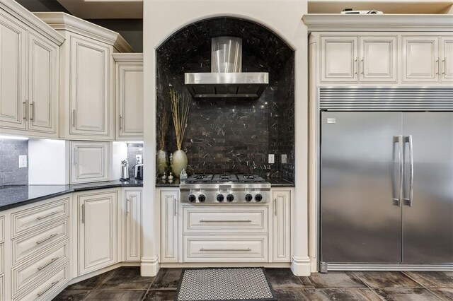 3617 Stagmoor Rd, Edmond, OK 73034 - kitchen featuring stainless steel appliances, wall chimney range hood, decorative backsplash, and dark stone counters