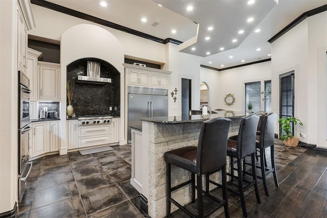 3617 Stagmoor Rd, Edmond, OK 73034 - kitchen with stainless steel appliances, crown molding, wall chimney range hood, backsplash, and an island with sink