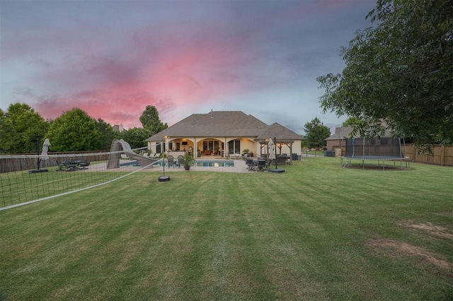3617 Stagmoor Rd, Edmond, OK 73034 - back of property at dusk featuring a trampoline, a patio area, and a fenced backyard