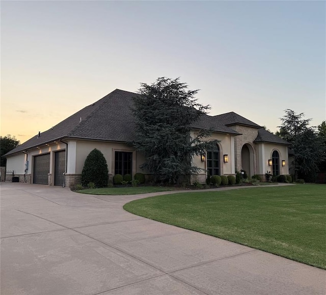 3617 Stagmoor Rd, Edmond, OK 73034 - french country inspired facade featuring concrete driveway, stucco siding, an attached garage, a front lawn, and a shingled roof