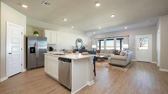 6113 Green Meadows Ln, Oklahoma City, OK 73132 - kitchen featuring stainless steel appliances, white cabinets, light wood-style floors, an island with sink, and recessed lighting
