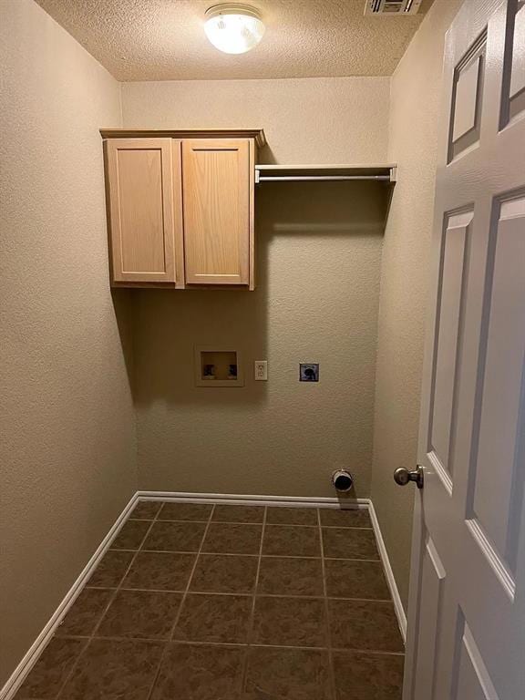 916 Beaumont Sq, Norman, OK 73071 - washroom featuring hookup for a washing machine, a textured ceiling, electric dryer hookup, dark tile patterned floors, and cabinet space