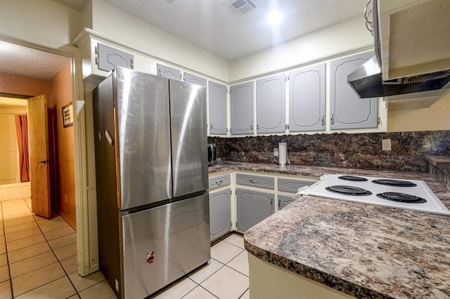 1383 N Peebly Rd, Choctaw, OK 73020 - kitchen with freestanding refrigerator, light tile patterned floors, white range with electric stovetop, dark countertops, and decorative backsplash