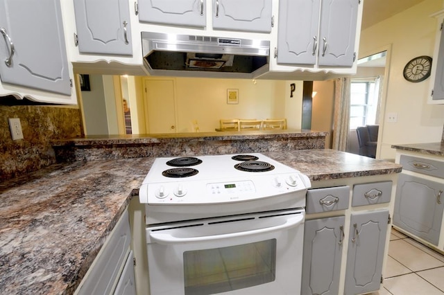 1383 N Peebly Rd, Choctaw, OK 73020 - kitchen featuring electric range, range hood, light tile patterned floors, dark countertops, and a peninsula
