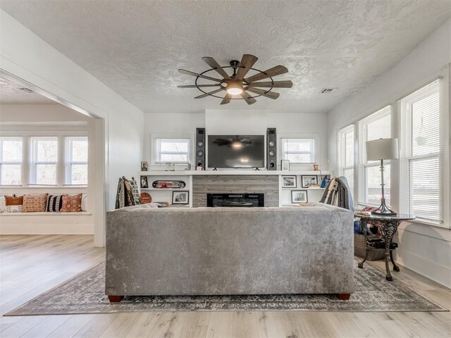 1317 N Wisconsin Ave, Oklahoma City, OK 73117 - living room with wood finished floors, a ceiling fan, a fireplace, and a textured ceiling