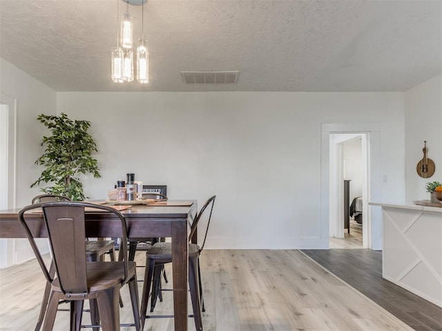 1317 N Wisconsin Ave, Oklahoma City, OK 73117 - dining space featuring light wood finished floors, a textured ceiling, and a chandelier
