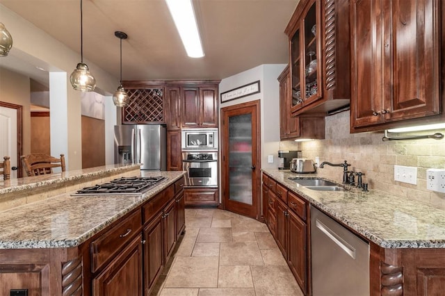 4417 Man O War Dr, Edmond, OK 73025 - kitchen featuring appliances with stainless steel finishes, backsplash, glass insert cabinets, light stone counters, and hanging light fixtures